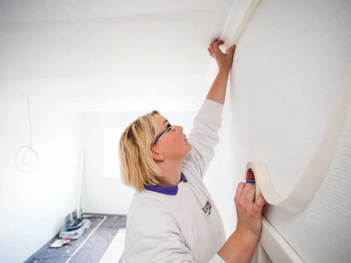 Maler Willenborg beim fachgerechten Tapezieren einer Wand