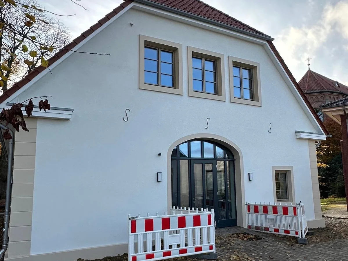 Dieselbe Hausfassade nach der Sanierung, frischer weißer Anstrich