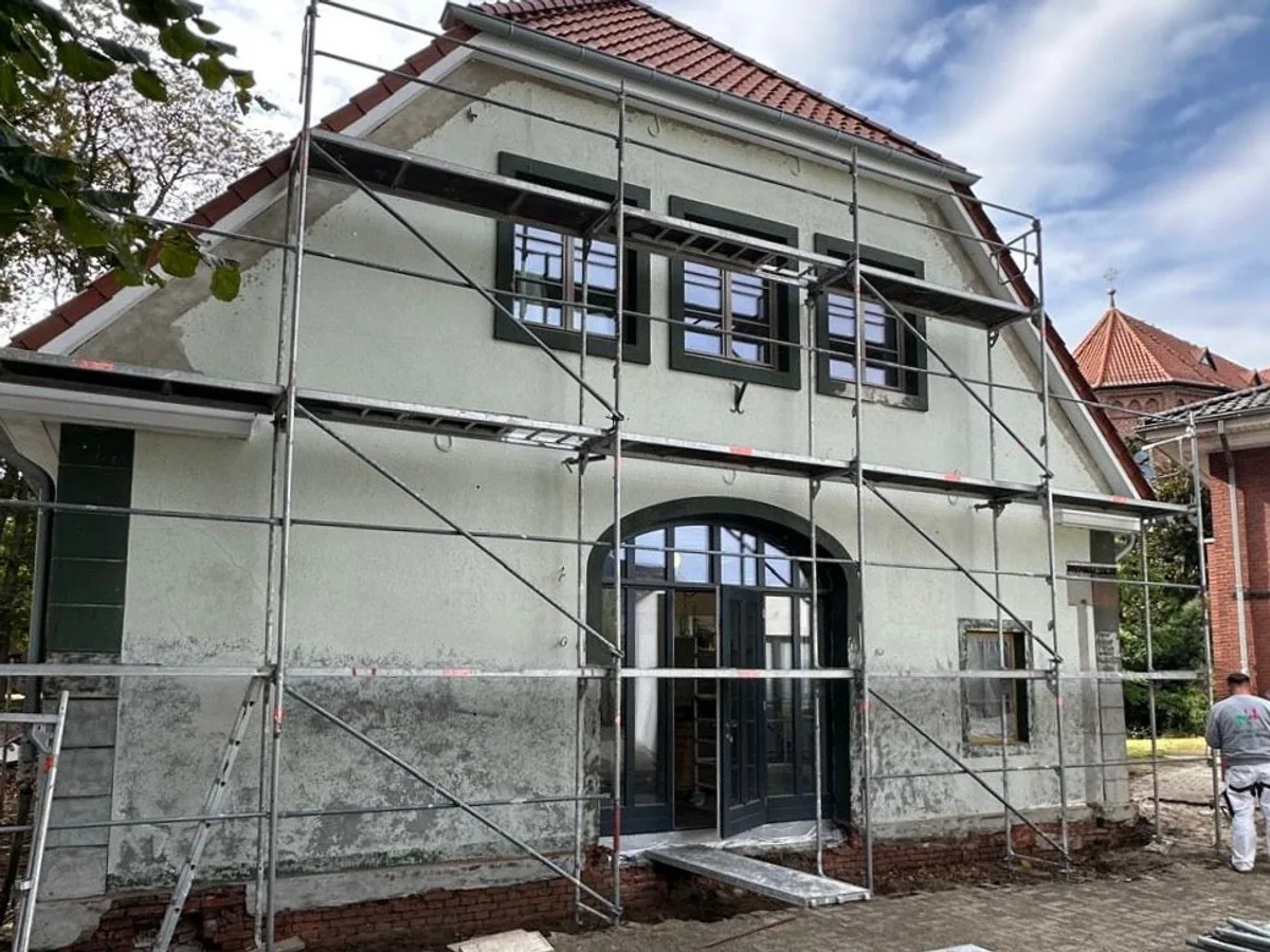 Hausfassade vor der Sanierung, verwitterter Putz mit Gerüst